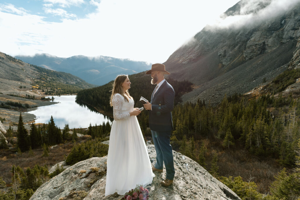 Couple on a rocky outcropping reading vows.