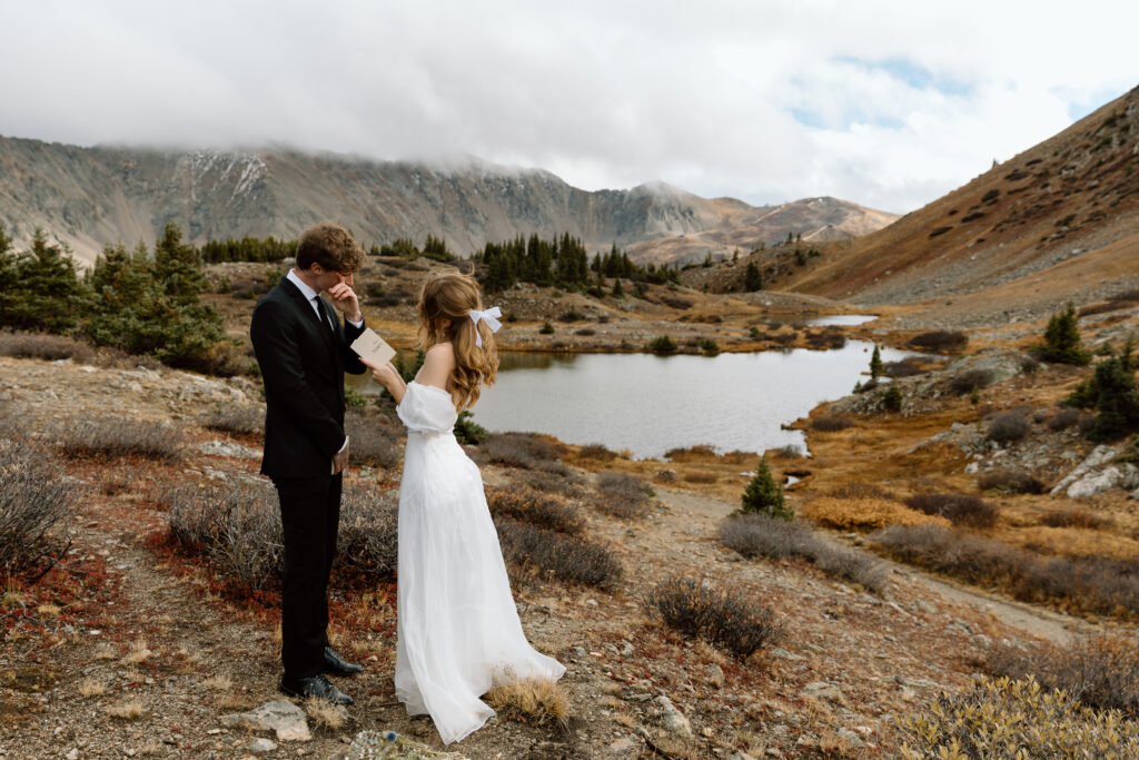 Couple reading their vows in front of an alpine lake.