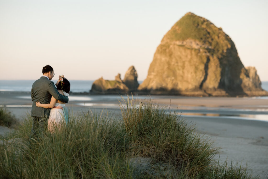 Couple embracing while looking toward Haystack Rock