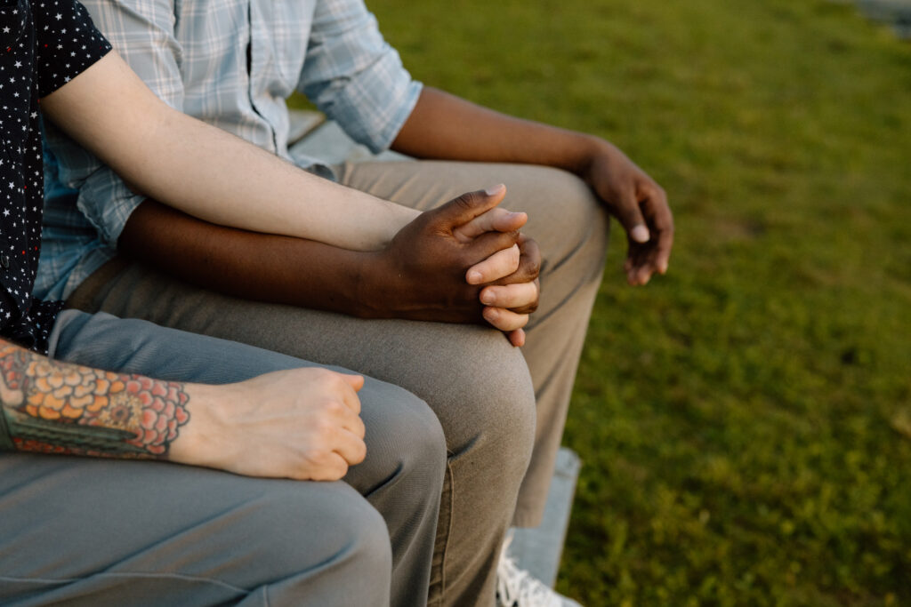 Couple holding hands while sitting on a bench.