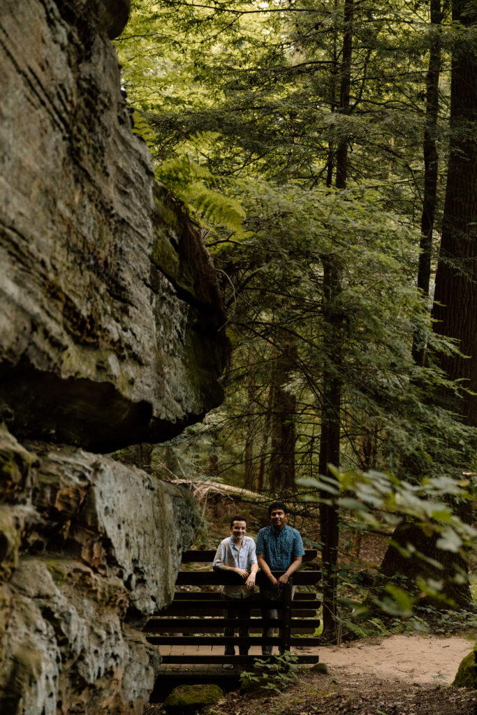 Couple leaning on a wooden bridge.