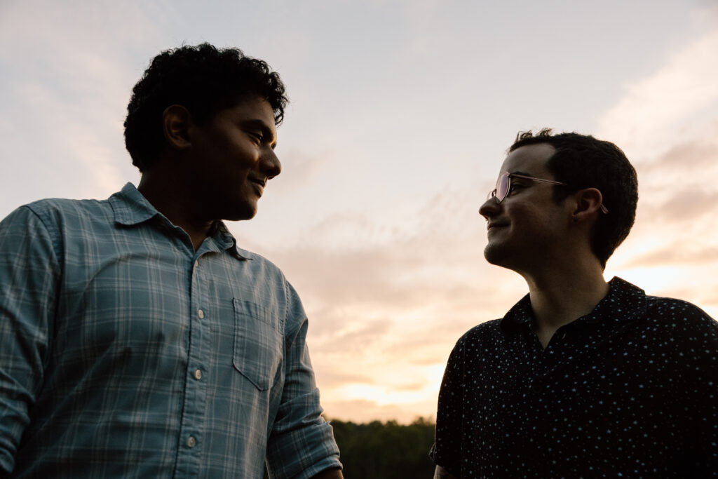 Couple looking at each other with the sunset behind them.