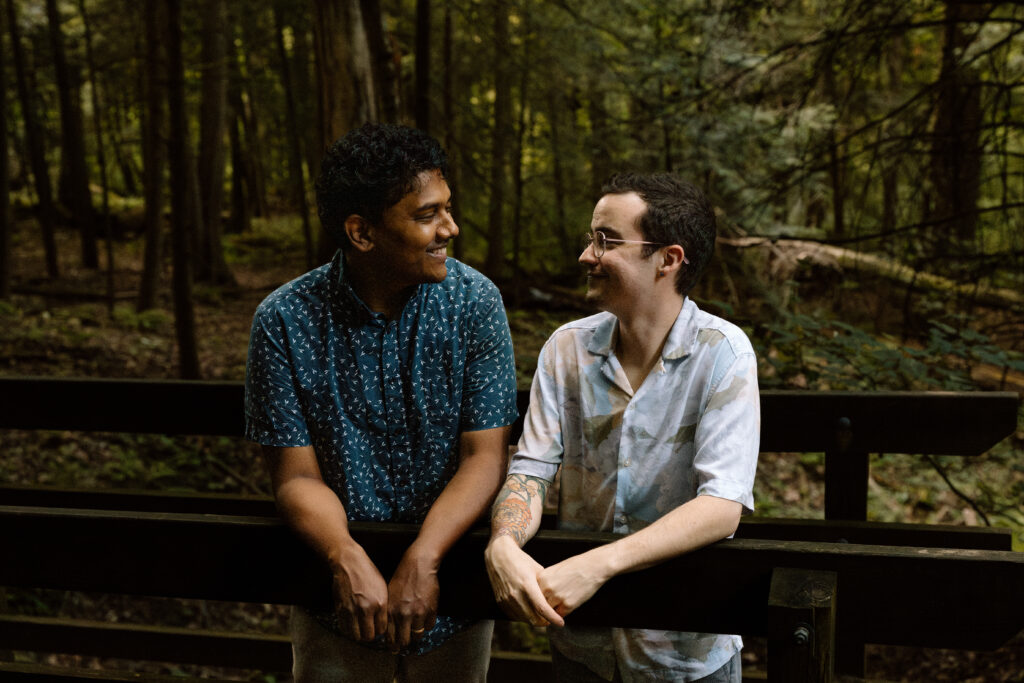 Couple leaning on a wooden bridge.