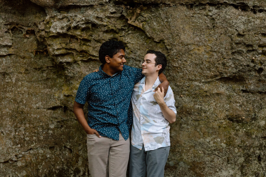 Couple embracing and leaning against a rocky ledge.