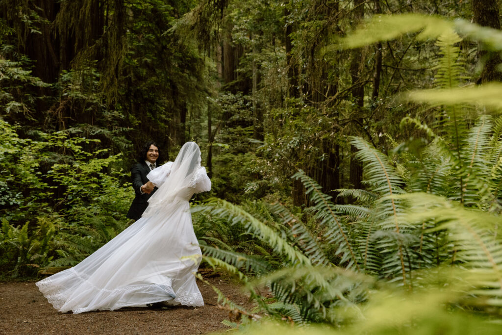 Couple spinning in a redwoods grove.
