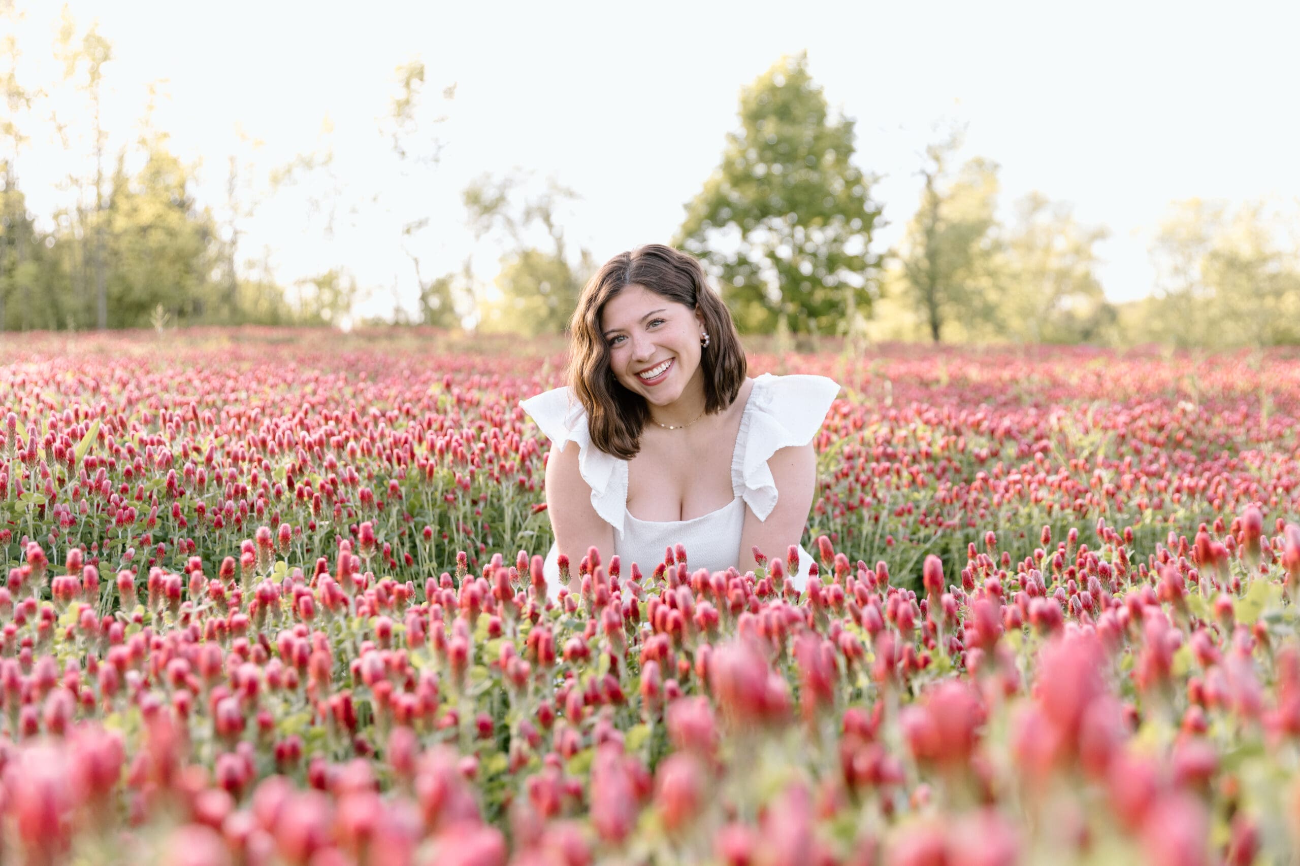 Photo of a woman sitting in a field of red flowers.