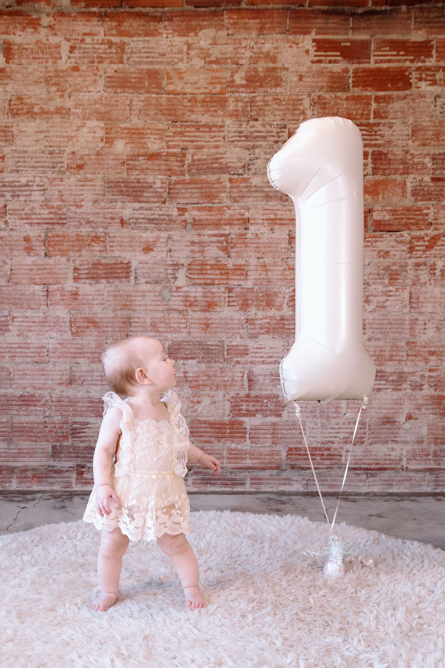 Child looking up at first birthday balloon.