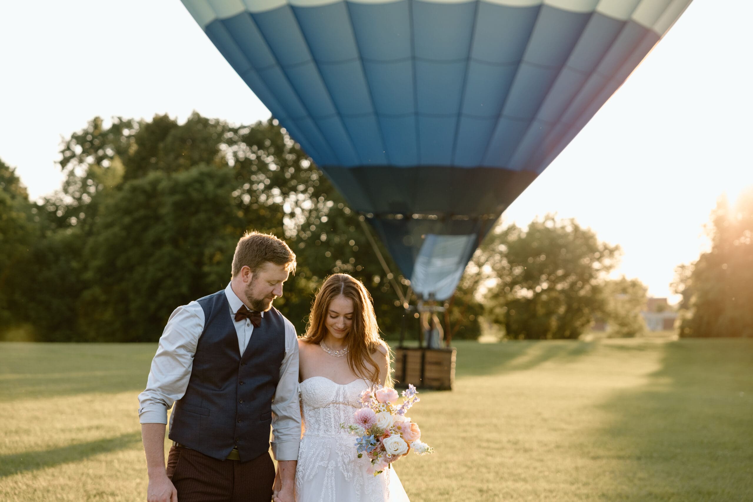 Groom and bride walking away from a hot air balloon.