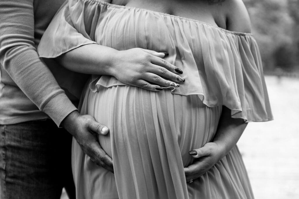 Black and white close up image of a couple holding mom's belly.